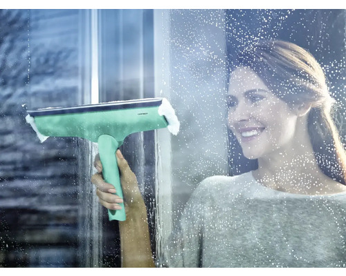 Frau reinigt Fenster mit einem Fensterwischer