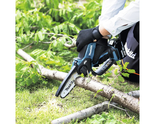 Person schneidet Ast mit Akku-Kettensäge von Makita