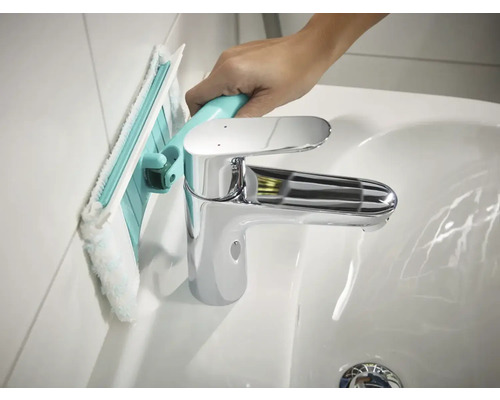 Reinigung einer Badezimmerwand mit einem Badwischer neben einem Waschbecken.