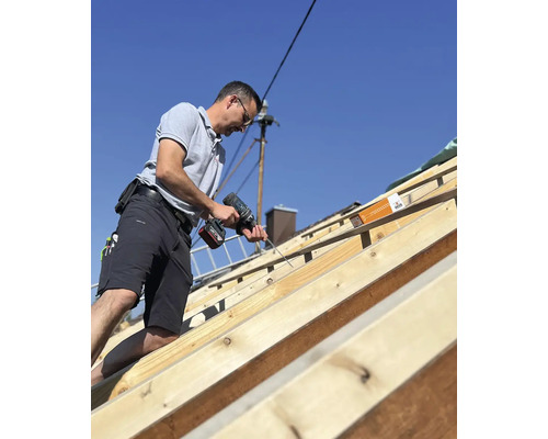 Handwerker befestigt Dachlatten mit einem Akkuschrauber.