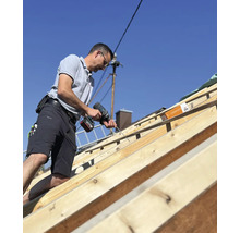 Handwerker befestigt Dachlatten mit einem Akku-Bohrschrauber.