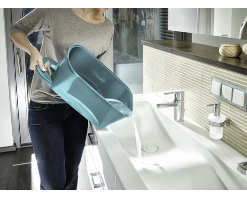 Frau leert einen Mehrzweckeimer in ein Waschbecken im Badezimmer