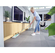 Frau wischt Boden mit Mopp in modernem Wohnzimmer