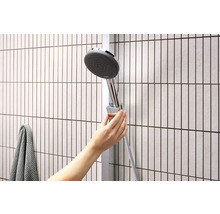 Hand verstellt Duschkopf an Duschstange im Badezimmer.