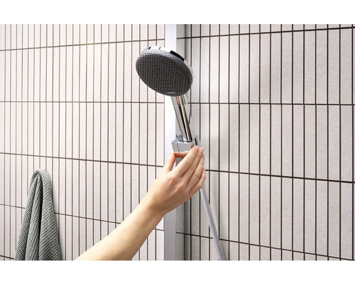 Hand verstellt Duschkopf an Duschstange im Badezimmer.