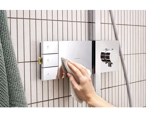 Hand reinigt Duscharmatur von Hansgrohe im Badezimmer.