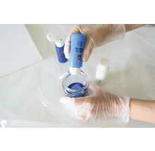 Eine Person mischt blaue Gießharzfarbe in einem Glasbehälter für Kunstprojekte.