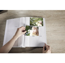 Offenes Fotoalbum mit Person, die Fotos einfügt