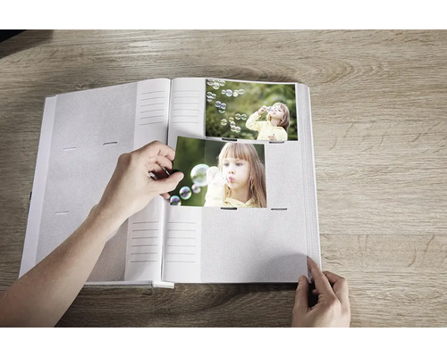 Offenes Fotoalbum mit Person, die Fotos einfügt