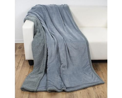 Graue Kuscheldecke auf einem weißen Sofa