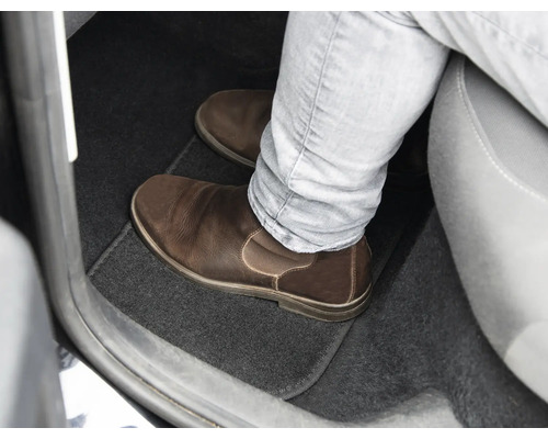 Fußraum eines Autos mit Fußmatte und Lederschuh