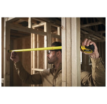 Handwerker misst mit einem Rollbandmass im Rohbau
