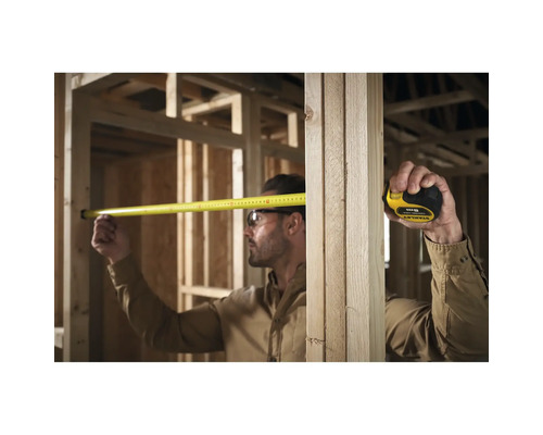 Handwerker misst mit einem Rollbandmass im Rohbau