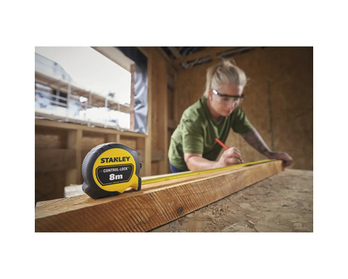 Frau misst Holz mit einem Stanley Rollbandmaß mit 8 Metern Länge