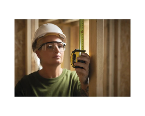 Frau misst mit einem Stanley Rollbandmass 8 m in einem Holzrahmenbau
