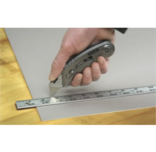 Hand schneidet Material mit Stanley Cuttermesser und Lineal