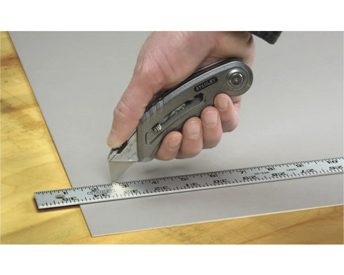 Hand schneidet Material mit Stanley Cuttermesser und Lineal