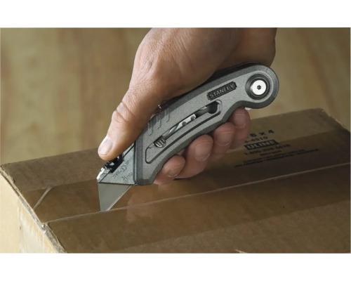 Eine Hand schneidet mit einem Stanley-Messer einen Karton auf.