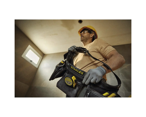 Handwerker mit Stanley Werkzeugtasche und Messband auf einer Baustelle