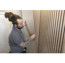 Mann montiert Akustikpaneele an der Wand zur Schallabsorption