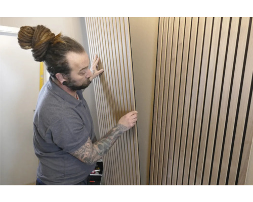 Mann montiert Akustikpaneele an der Wand zur Schallabsorption