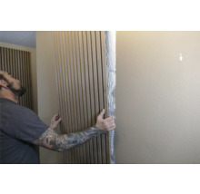 Mann befestigt Akustikpaneele an der Wand zur Schallabsorption und Wandgestaltung.