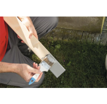 Eine Person streicht ein Holzbrett mit einem Pinsel.