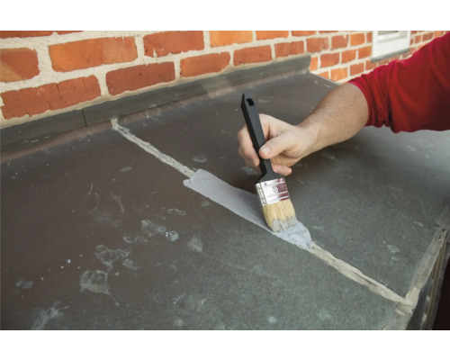 Eine Person versiegelt mit einem Pinsel Fugen an einer Blechverkleidung.