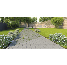 Gartenansicht mit Rasenfläche, Steinweg und Sitzgruppe auf einer Holzterrasse