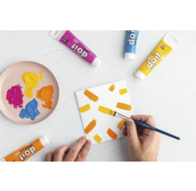 Szene mit Farbtuben, Pinsel und bemalter Leinwand für Bastelarbeiten