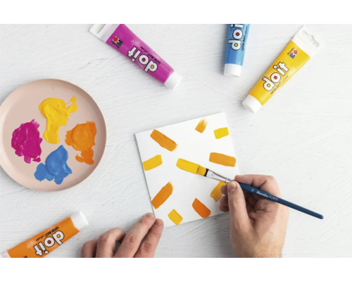 Szene mit Farbtuben, Pinsel und bemalter Leinwand für Bastelarbeiten