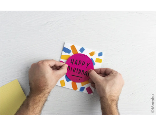 Person bastelt eine Geburtstagskarte mit der Aufschrift Happy Birthday.