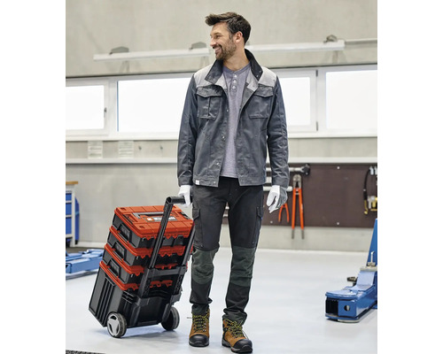 Handwerker mit Werkzeugkoffer auf Rädern in einer Werkstatt