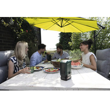 Gruppe von Personen beim Essen im Freien unter einem Sonnenschirm mit einem Bosch-Produkt auf dem Tisch.