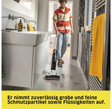 Mann benutzt Nass-Trockensauger im Badezimmer zur Reinigung von verschütteten Flüssigkeiten auf dem Boden