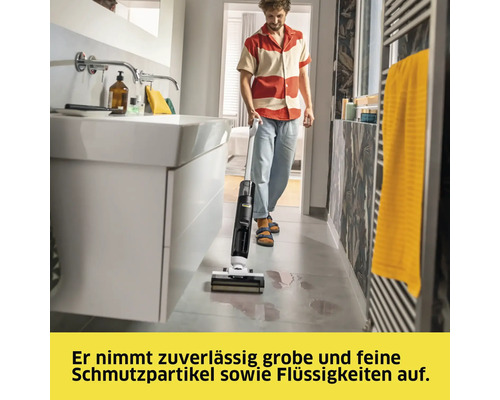 Mann benutzt Nass-Trockensauger im Badezimmer zur Reinigung von verschütteten Flüssigkeiten auf dem Boden