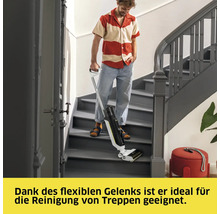Ein Mann reinigt mit einem Akku-Wischsauger eine Treppe in einem Haus.