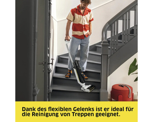Ein Mann reinigt mit einem Akku-Wischsauger eine Treppe in einem Haus.