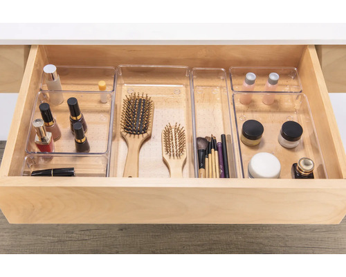 Geöffnete Schublade mit durchsichtigen Organizer-Einsätzen für Kosmetikartikel und Bürsten.