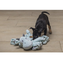 Welpe spielt mit Plüschtier auf dem Boden.