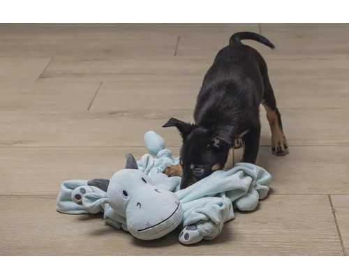 Welpe spielt mit Plüschtier auf dem Boden.