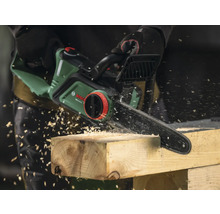 Elektrische Kettensäge beim Sägen von Holz mit Holzspänen