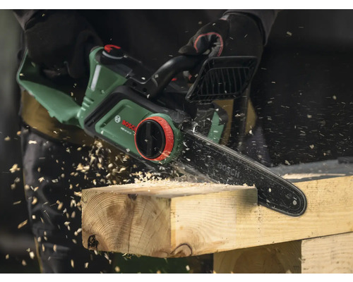 Elektrische Kettensäge beim Sägen von Holz mit Holzspänen