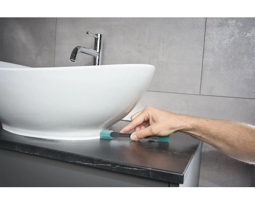 Szene eines Badezimmers mit einem Waschbecken und einer Person, die eine Reinigungsbürste benutzt