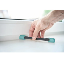 Eine Person benutzt einen Fensterkeil, um ein Fenster zu öffnen.