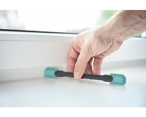 Eine Person benutzt einen Fensterkeil, um ein Fenster zu öffnen.