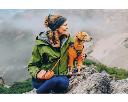 Frau mit Hund auf einem Felsen in den Bergen