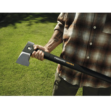 Person hält eine Fiskars Ultra Spaltaxt vor grünem Hintergrund