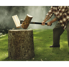 Mann spaltet Holzscheit mit einer Axt auf einem Hackklotz