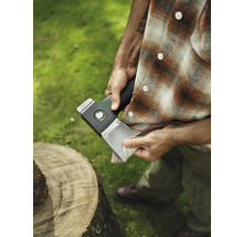 Mann reinigt Axtklinge neben Baumstamm